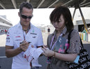 Michael Schumacher signs autographs as he arrives in the paddock
