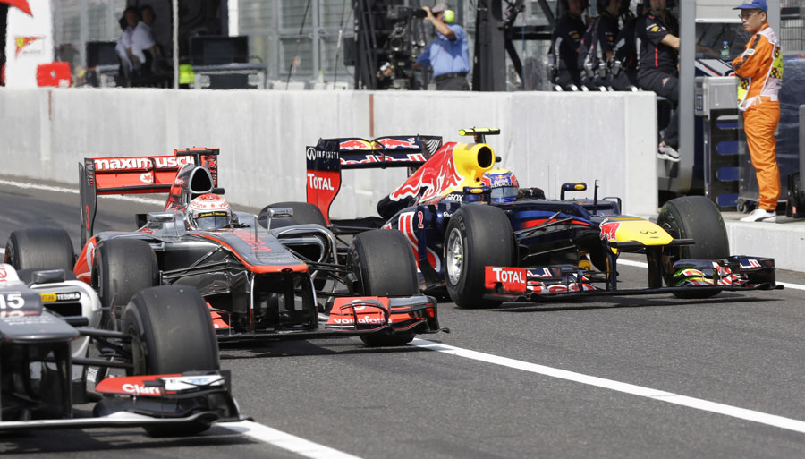 Mark Webber passes Jenson Button and Sergio Perez in the pit lane