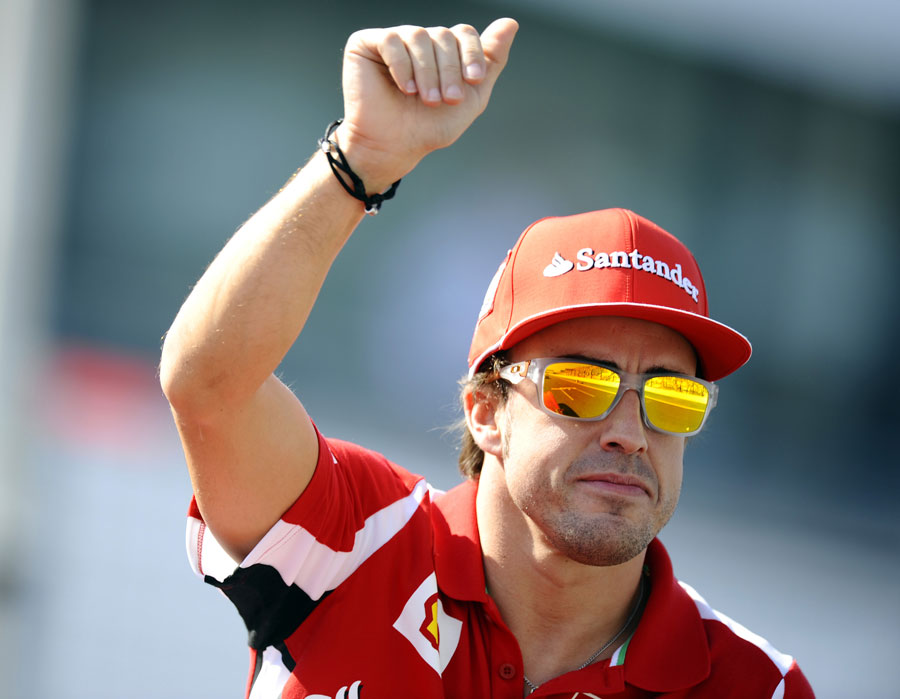 Fernando Alonso waves to the crowd on the drivers' parade