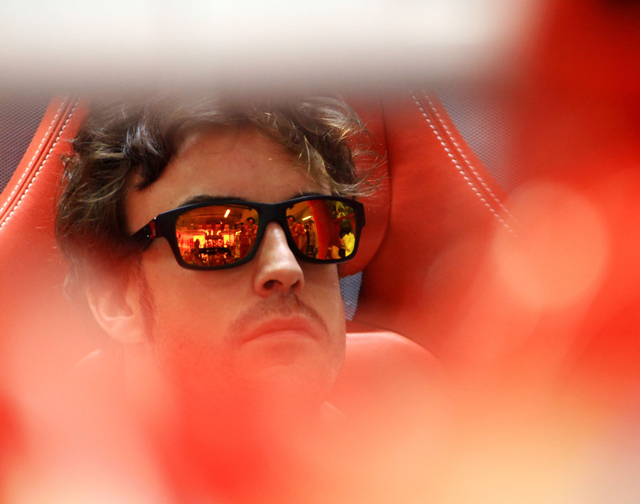 Fernando Alonso keeps an eye on work in the Ferrari garage