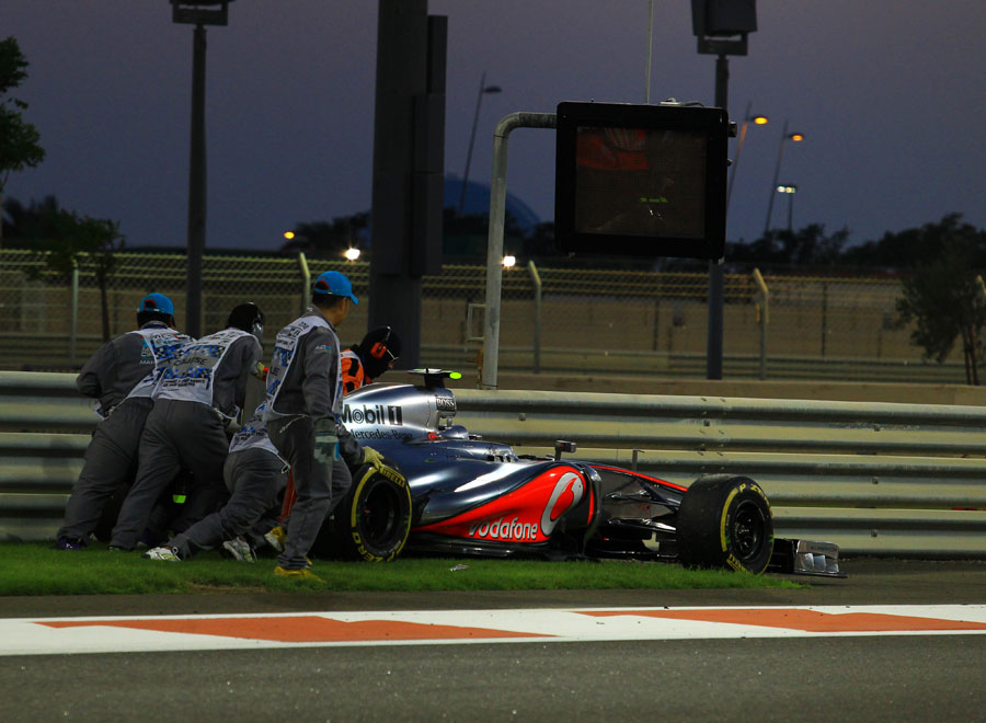 Lewis Hamilton's McLaren is pushed away by marshals after he retired from the lead
