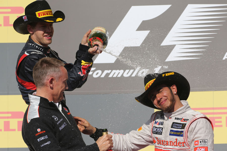 A stetson-wearing Sebastian Vettel sprays Martin Whitmarsh and Lewis Hamilton