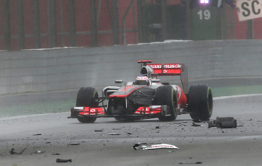 Jenson Button weaves his way through the debris of Paul di Resta's Force India