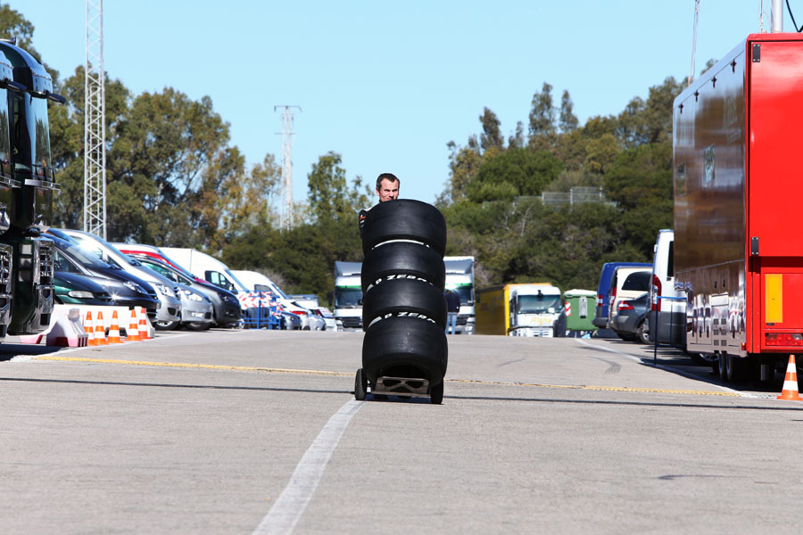 An McLaren mechanic wheels some new Pirelli tyres through the paddock