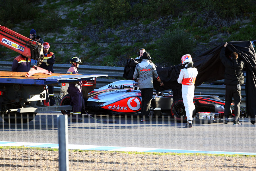 Jenson Button helps McLaren cover the MP4-27 after stopping on track