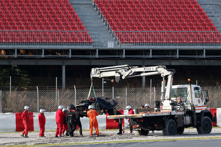 Romain Grosjean's Lotus is recovered from the gravel after he spun off