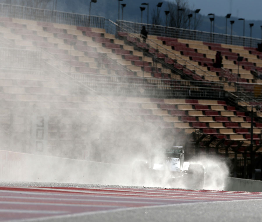Lewis Hamilton leaves a trail of spray behind him on the pit straight