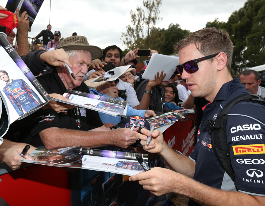 Sebastian Vettel signs autographs as he arrives in the paddock