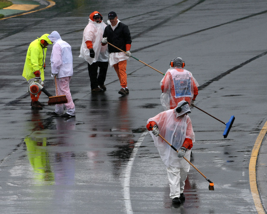 The story of the day as marshals try to sweep water off the track