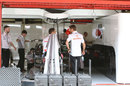 Jenson Button keeps an eye on work in the McLaren garage