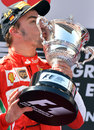 Fernando Alonso kisses his winner's trophy on the podium
