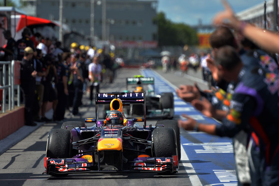 Red Bull mechanics applaud Sebastian Vettel as he returns to the pits
