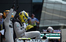 Nico Rosberg climbs out of his car as team-mate Lewis Hamilton celebrates