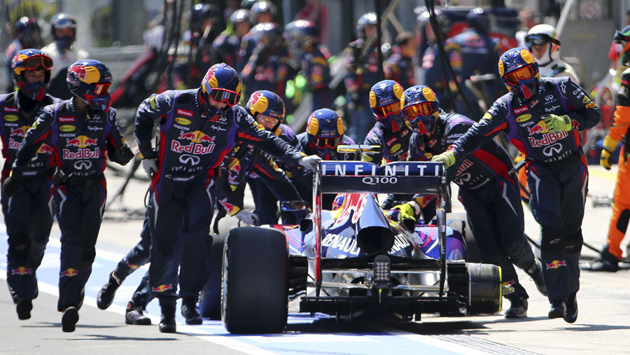 Mark Webber is wheeled back up the pit lane after losing a tyre