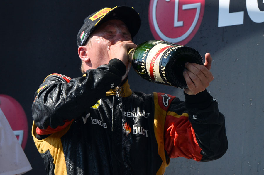 A soaked Kimi Raikkonen takes a swig of champagne