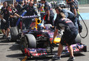 Sebastian Vettel is wheeled back in to the Red Bull garage after his puncture