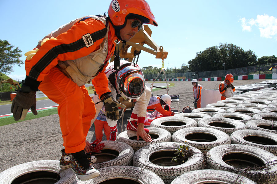 Jules Bianchi clambers over the tyre wall after crashing out in FP1