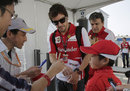 Fernando Alonso signs an autograph for a young fan when he arrives at the track on Saturday