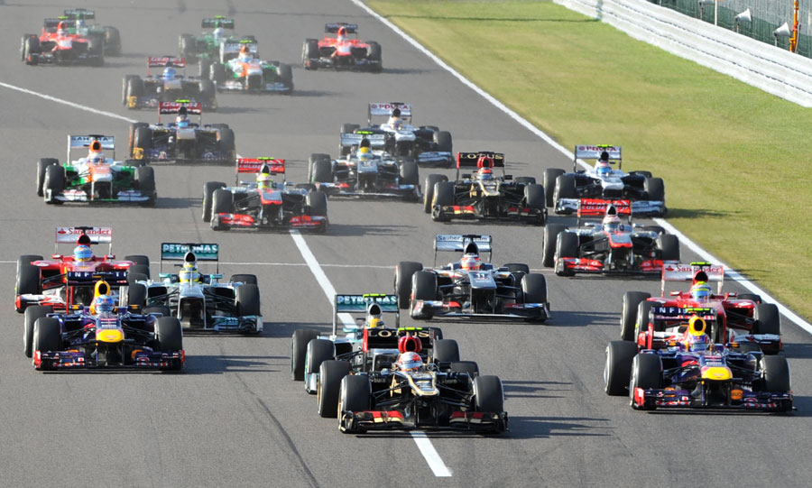 Romain Grosjean leads the pack into Turn 1 as Lewis Hamilton's tyre deflates following contact with Sebastian Vettel