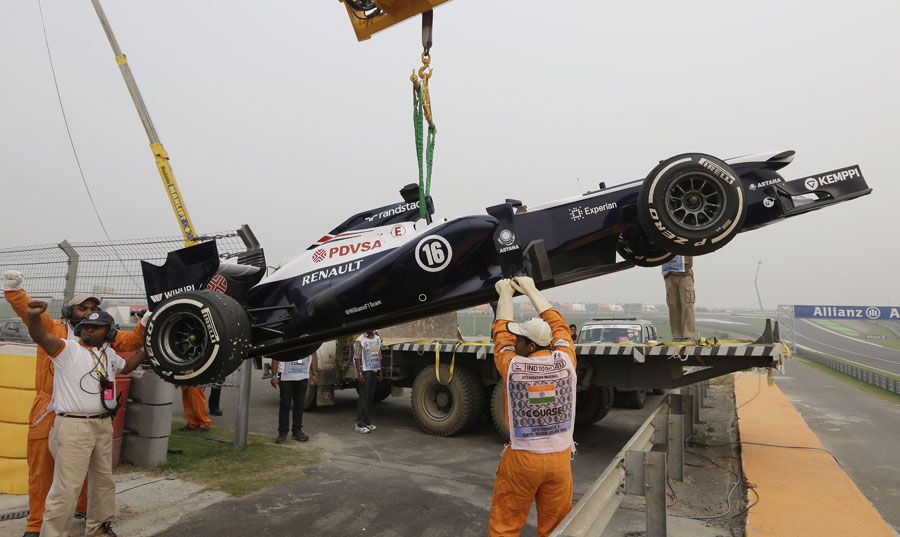 Pastor Maldonado's Williams is craned away after a wheel nut fell off