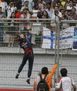 Sebastian Vettel climbs on to a fence to throw his gloves in to the crowd