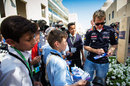Sebastian Vettel signs autographs for young fans in the paddock