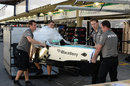 Mercedes mechanics unpack a tub in the pit lane