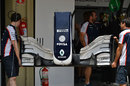 A Williams front wing is carried in to the garage