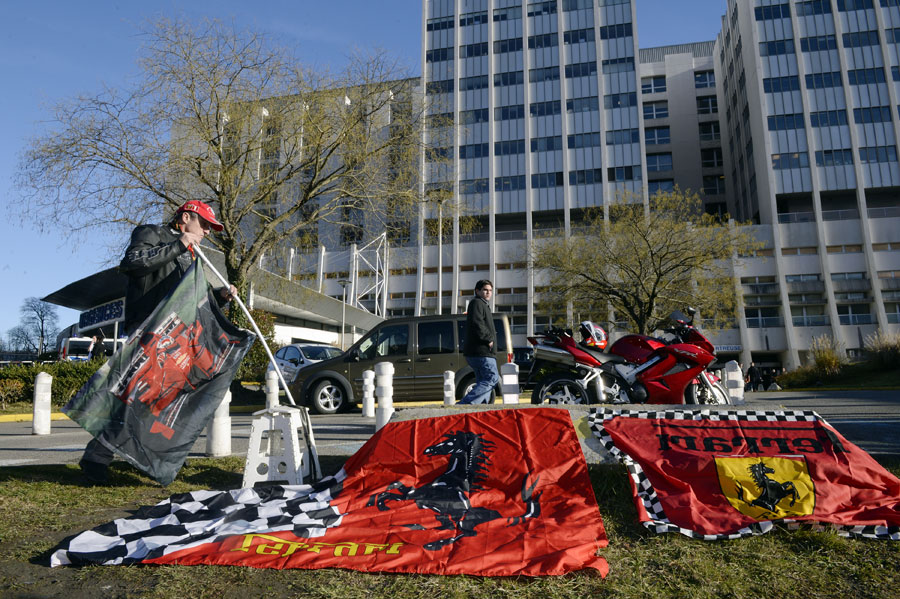 A fan lays out flags outside the Centre Hospitalier Universitaire in Grenoble where Michael Schumacher is being treated for head injuries