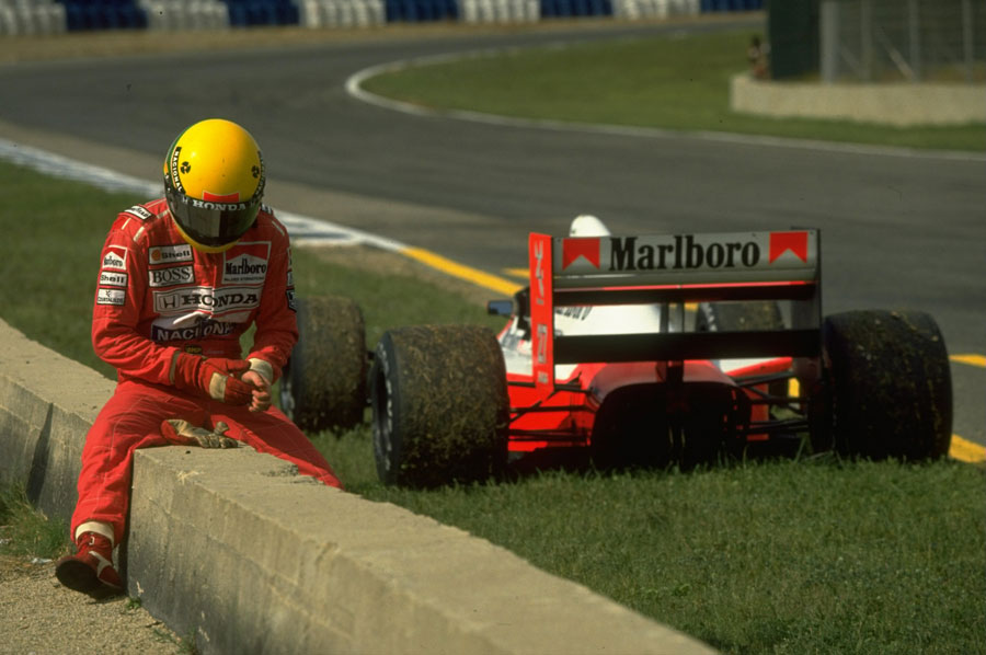 Ayrton Senna sits on a wall at the side of the track