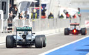 Nico Rosberg heads down the pit lane with a Lotus in the distance