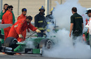 A marshall sees to Marcus Ericsson's Caterham with a fire extinguisher
