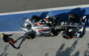 A marshal puts out a fire on the back of Adrian Sutil's Sauber