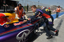 Sebastian Vettel helps marshals push his Red Bull back down the pit lane