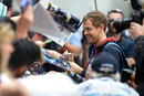 Sebastian Vettel signs autographs on his arrival at the circuit