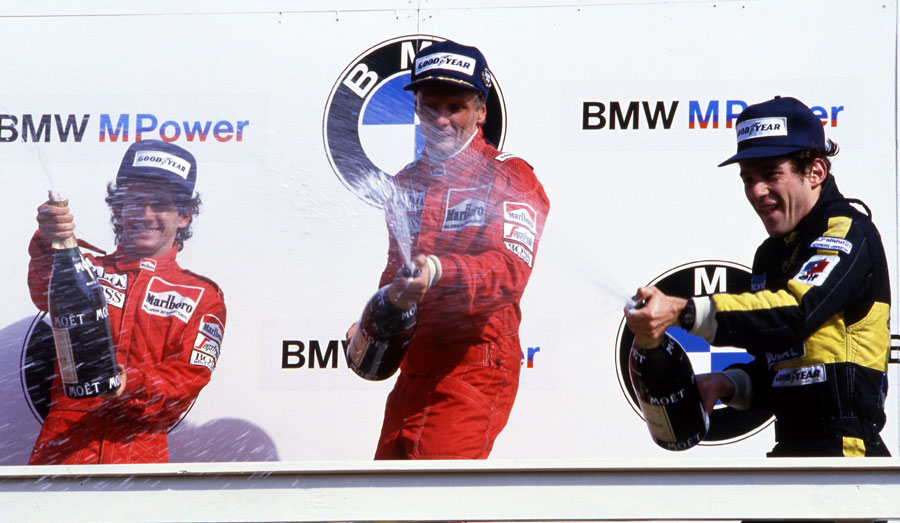 Niki Lauda celebrates his final career win alongside Alain Prost and Ayrton Senna