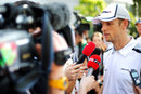Jenson Button talks to the media in the paddock