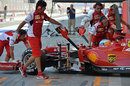 Mechanics push Fernando Alonso back into the Ferrari garage