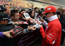 Kimi Raikkonen signs autographs for fans in the pit lane