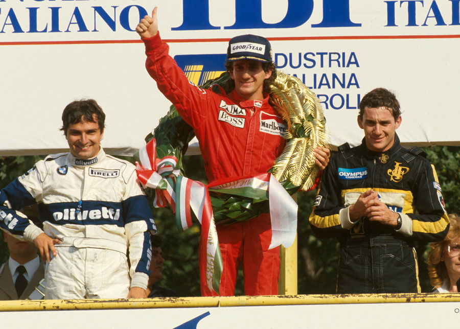 Alain Prost stands on the podium, flanked by Nelson Piquet and Ayrton Senna