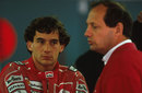 Ayrton Senna watches on as Ron Dennis talks in the paddock