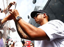Lewis Hamilton signs an autograph in the paddock