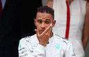 Lewis Hamilton rubs dirt from his eye on the podium