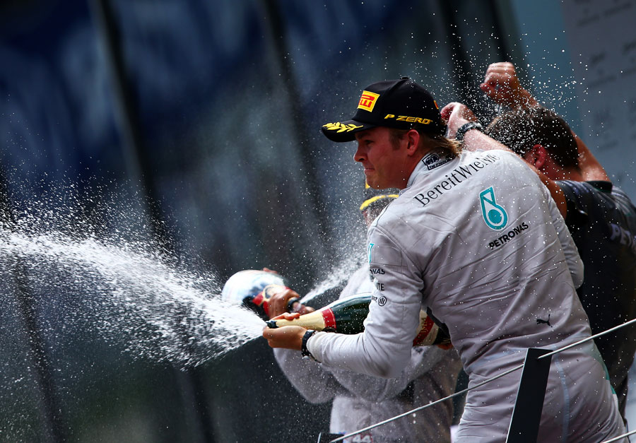 Nico Rosberg sprays the champagne onto his Mercedes team below the podium