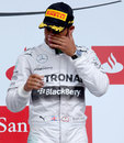 Race-winner Lewis Hamilton wipes his eyes on the podium