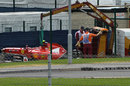 The wreckage of Kimi Raikkonen's Ferrari gets towed away after his first lap accident