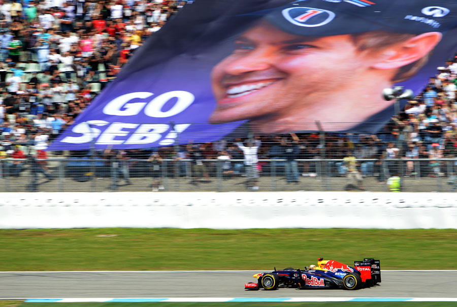 Sebastian Vettel roars past a banner of encouragement from his home fans