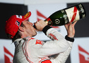 Jenson Button swigs champagne after his win