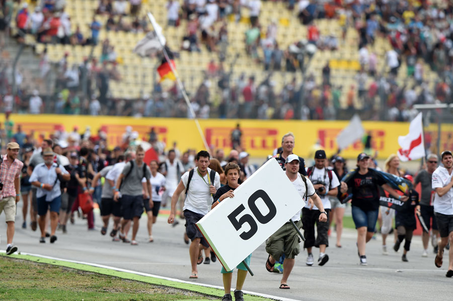 Fans run on to the circuit towards the podium ceremony