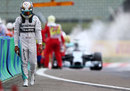 A dejected Lewis Hamilton walks back to the pits after his car caught fire in qualifying